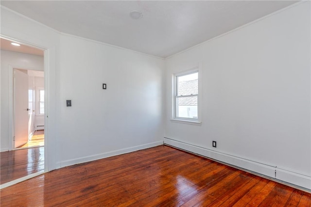 empty room featuring hardwood / wood-style flooring, ornamental molding, and a baseboard heating unit