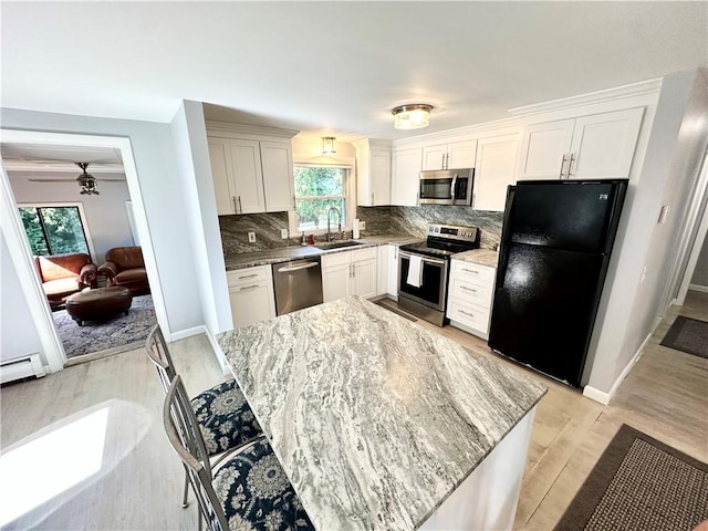 kitchen with tasteful backsplash, white cabinetry, sink, light stone counters, and stainless steel appliances