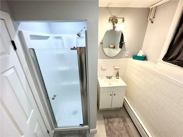 bathroom with tile walls, vanity, a baseboard heating unit, and an enclosed shower