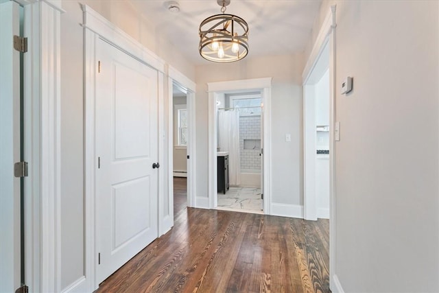 corridor with dark hardwood / wood-style flooring and a chandelier