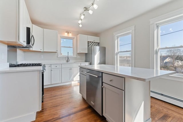 kitchen featuring stainless steel appliances, a center island, sink, and white cabinets