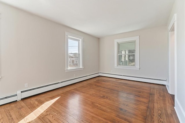 spare room featuring a baseboard heating unit and hardwood / wood-style flooring