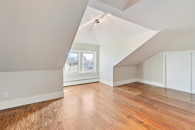 additional living space featuring lofted ceiling, a baseboard radiator, and light hardwood / wood-style floors