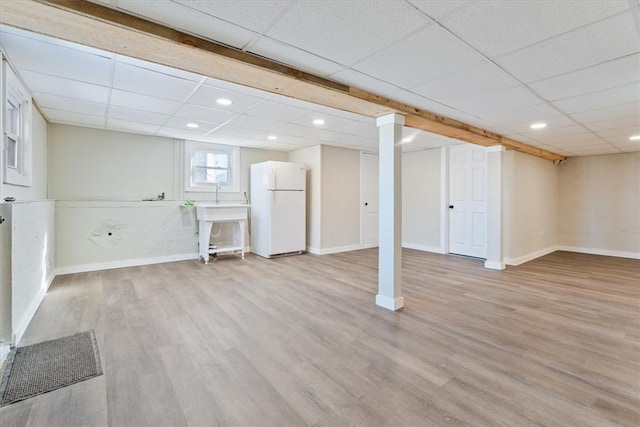 basement with light hardwood / wood-style flooring, a paneled ceiling, and white fridge