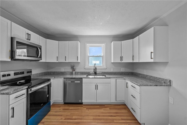 kitchen with sink, a textured ceiling, stainless steel appliances, light hardwood / wood-style floors, and white cabinets