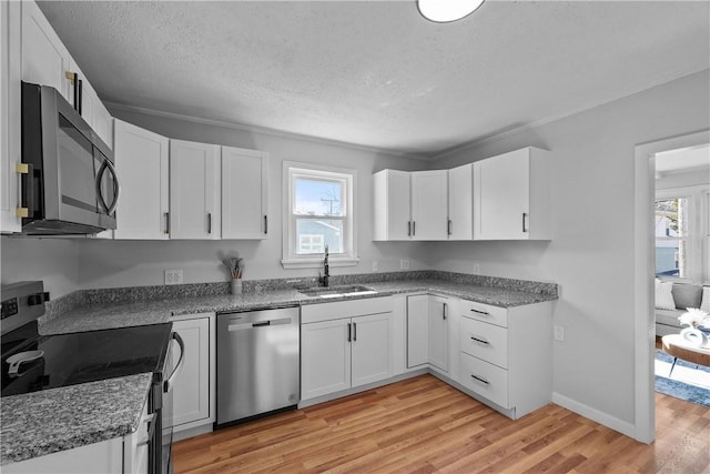 kitchen featuring appliances with stainless steel finishes, sink, light hardwood / wood-style flooring, and white cabinets