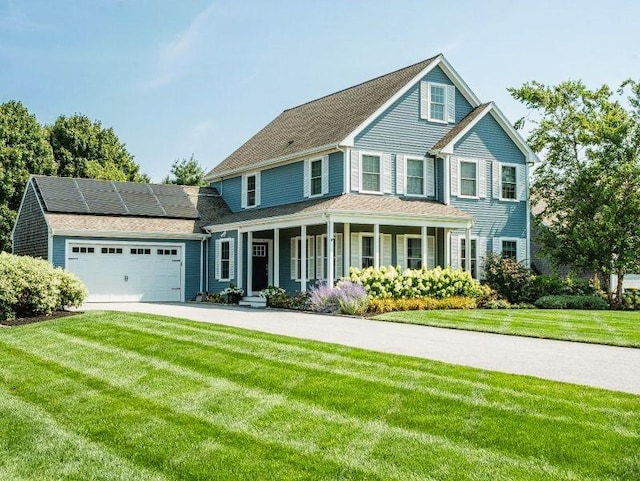 view of front of house featuring a garage, a front yard, solar panels, and a porch