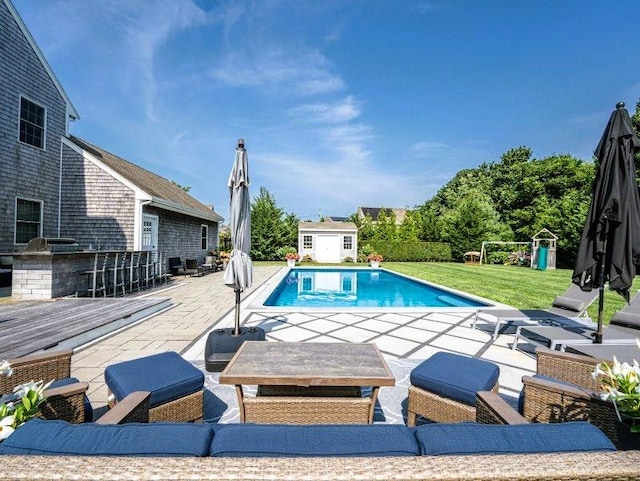 view of swimming pool with a patio, a yard, an outbuilding, and a bar