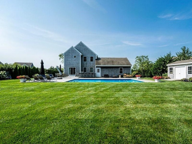 back of house featuring a patio, an outbuilding, and a lawn