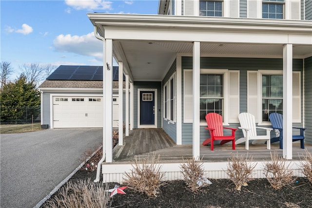 entrance to property featuring a garage, covered porch, and solar panels