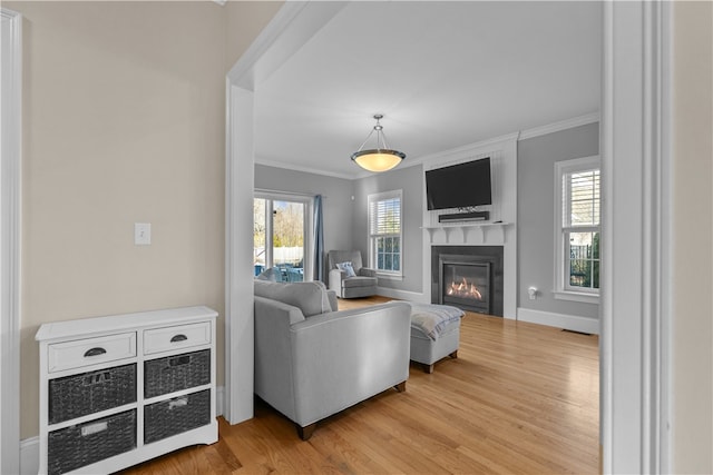 living room featuring crown molding, a healthy amount of sunlight, and light wood-type flooring