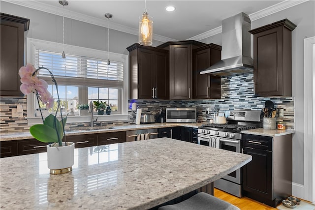 kitchen featuring appliances with stainless steel finishes, pendant lighting, sink, a breakfast bar area, and wall chimney exhaust hood