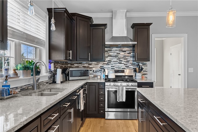 kitchen with stainless steel appliances, hanging light fixtures, sink, and wall chimney exhaust hood