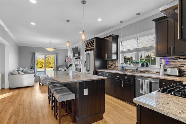 kitchen with light stone counters, sink, hanging light fixtures, and a kitchen island