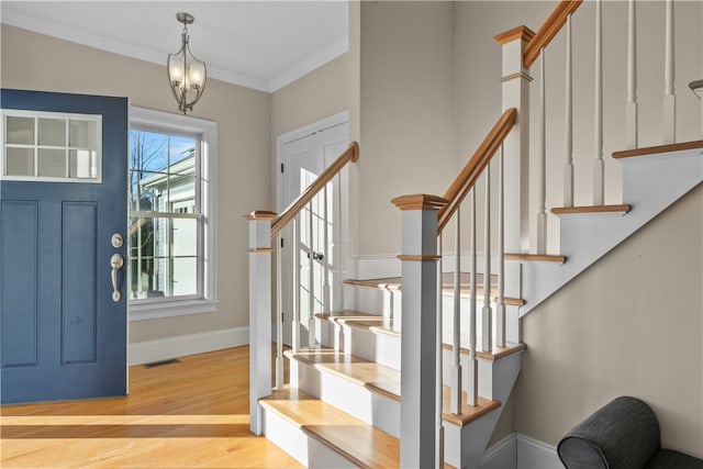 foyer entrance featuring ornamental molding and light hardwood / wood-style flooring