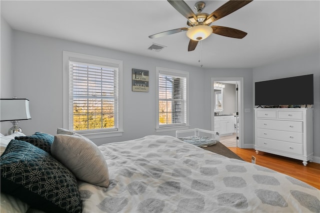 bedroom with ceiling fan, ensuite bathroom, and light wood-type flooring