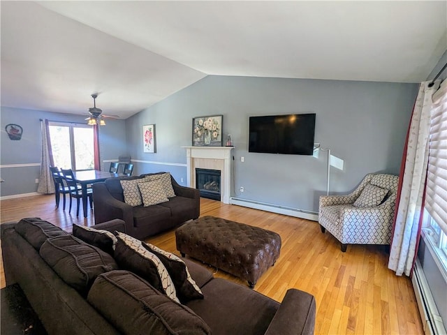 living room featuring a baseboard radiator, lofted ceiling, a fireplace, and light hardwood / wood-style flooring