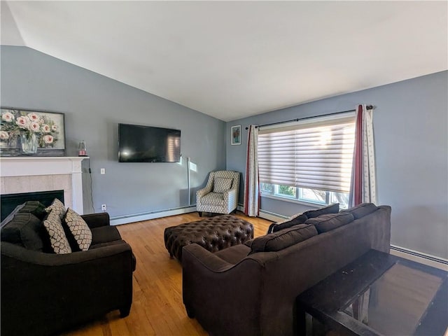 living room featuring a tiled fireplace, vaulted ceiling, and a baseboard heating unit