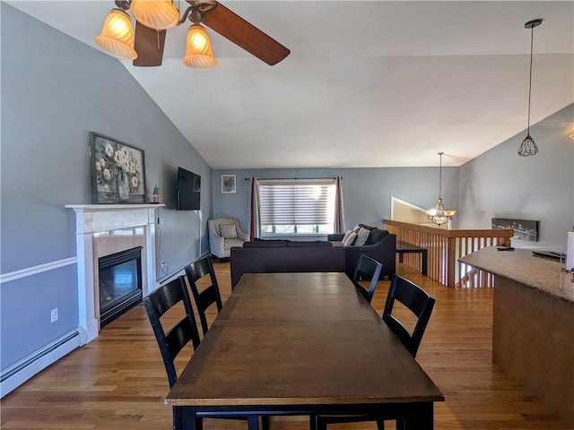 dining room featuring lofted ceiling, a baseboard heating unit, and light hardwood / wood-style flooring