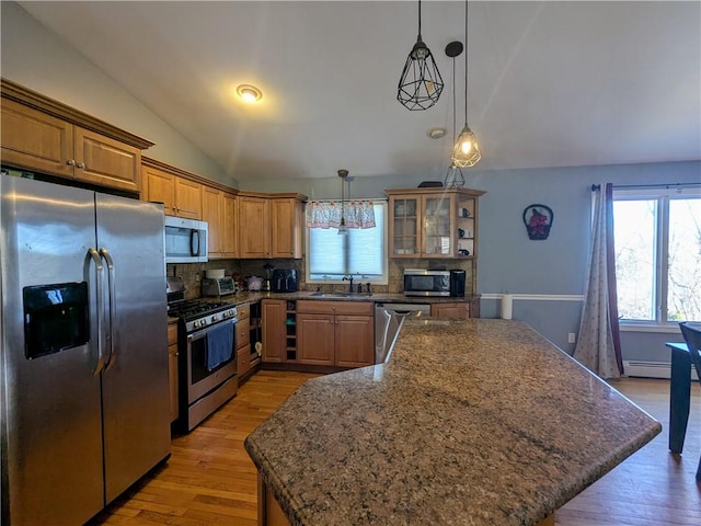 kitchen with lofted ceiling, sink, stainless steel appliances, a center island, and decorative light fixtures