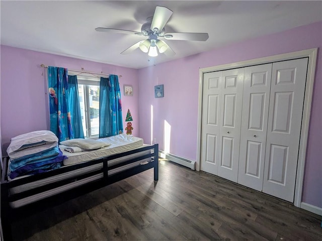 bedroom with dark wood-type flooring, ceiling fan, a closet, and a baseboard heating unit