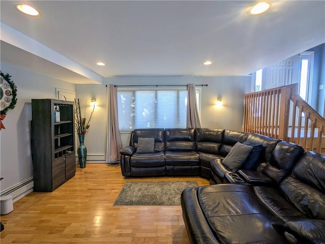 living room with a baseboard heating unit, light hardwood / wood-style flooring, and a healthy amount of sunlight