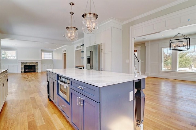 kitchen with appliances with stainless steel finishes, a kitchen island, hanging light fixtures, and white cabinets