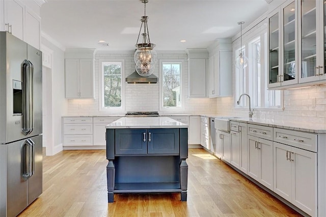 kitchen with sink, light hardwood / wood-style flooring, pendant lighting, stainless steel appliances, and white cabinets