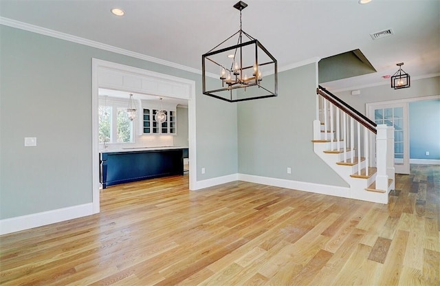 unfurnished living room with ornamental molding, a notable chandelier, and light hardwood / wood-style flooring