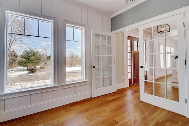 doorway to outside with crown molding, french doors, and light wood-type flooring