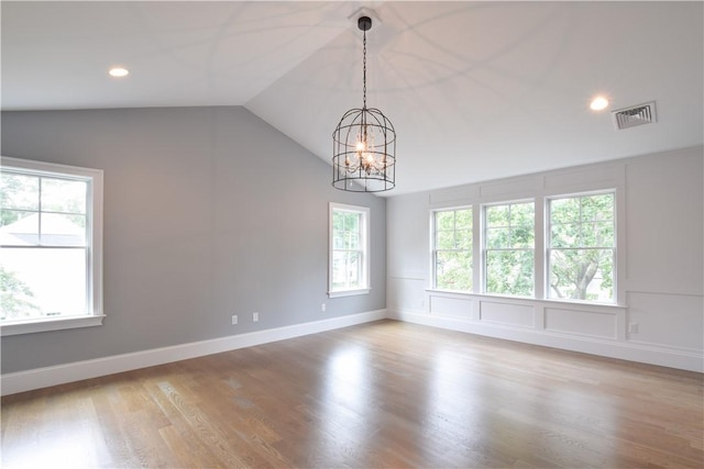 unfurnished room with lofted ceiling, light hardwood / wood-style floors, and a chandelier