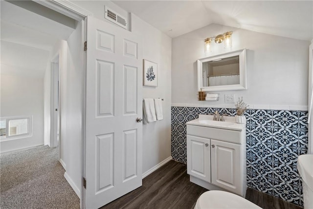 bathroom featuring lofted ceiling, vanity, hardwood / wood-style floors, and tile walls