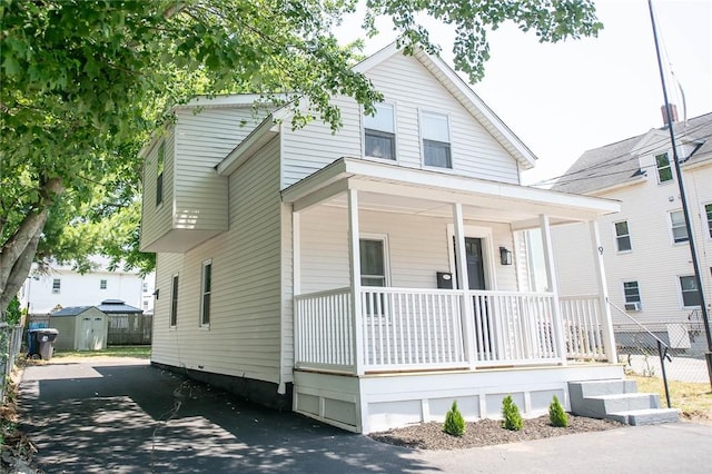 view of front of property featuring a porch and a storage shed