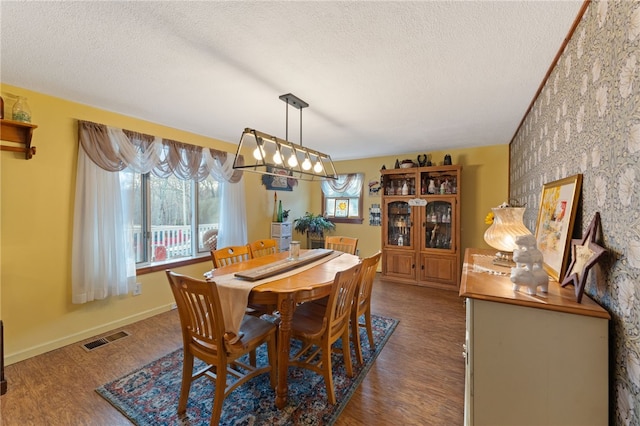 dining area featuring dark wood-type flooring and a textured ceiling