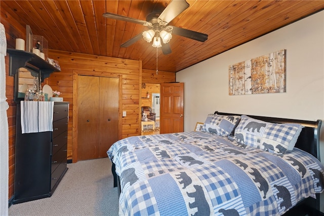 carpeted bedroom with ceiling fan, wooden walls, a closet, and wooden ceiling