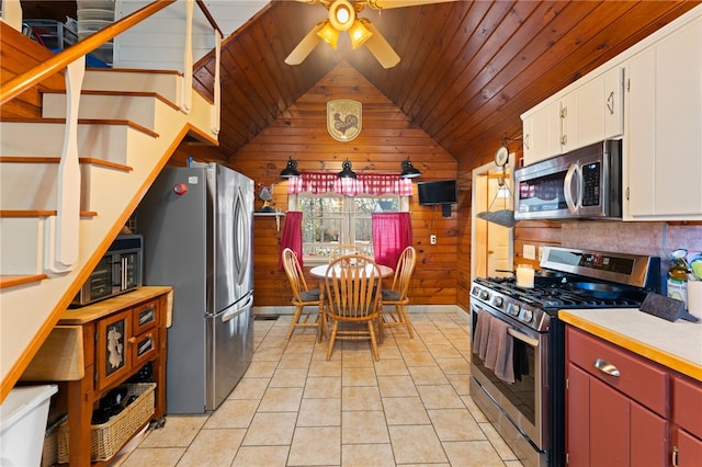 kitchen featuring light tile patterned floors, wooden walls, stainless steel appliances, white cabinets, and wooden ceiling