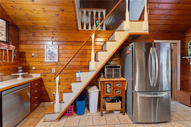 kitchen featuring appliances with stainless steel finishes, wood walls, lofted ceiling, light tile patterned floors, and wooden ceiling