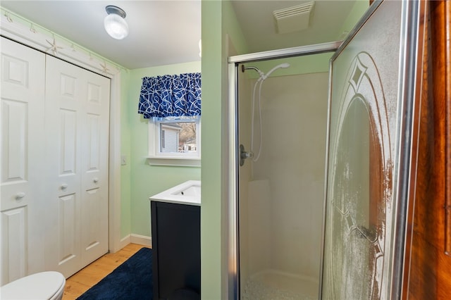 bathroom with hardwood / wood-style flooring, vanity, toilet, and an enclosed shower