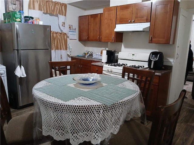 kitchen with stainless steel fridge, white gas range oven, and hardwood / wood-style floors