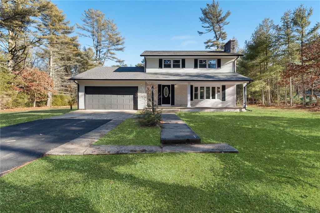 view of front of home featuring a garage, a front lawn, and covered porch