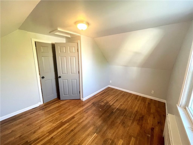 additional living space with hardwood / wood-style floors, vaulted ceiling, and a baseboard heating unit