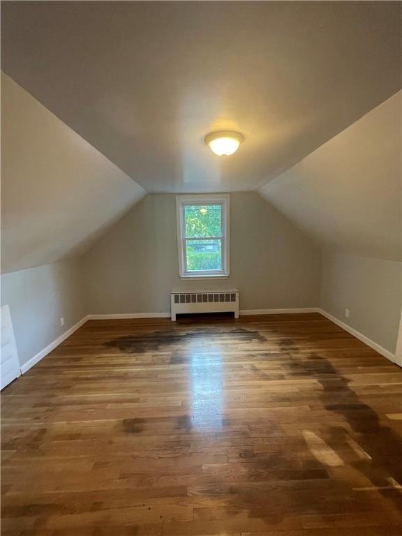 bonus room with vaulted ceiling, radiator, and dark hardwood / wood-style flooring