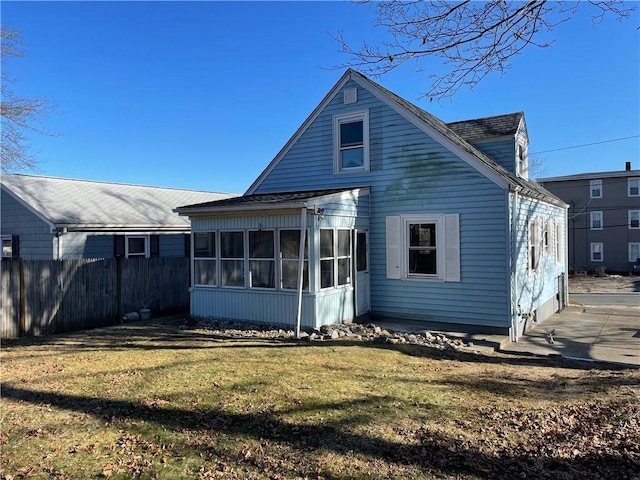 rear view of property featuring a lawn and a sunroom