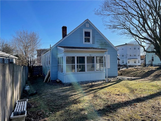 rear view of house featuring a yard and a sunroom