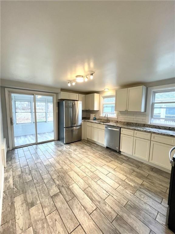 kitchen featuring sink, stainless steel appliances, tasteful backsplash, white cabinets, and light wood-type flooring