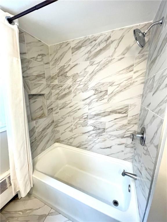 bathroom featuring shower / tub combo with curtain and a baseboard heating unit