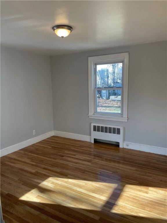 spare room with dark wood-type flooring and radiator