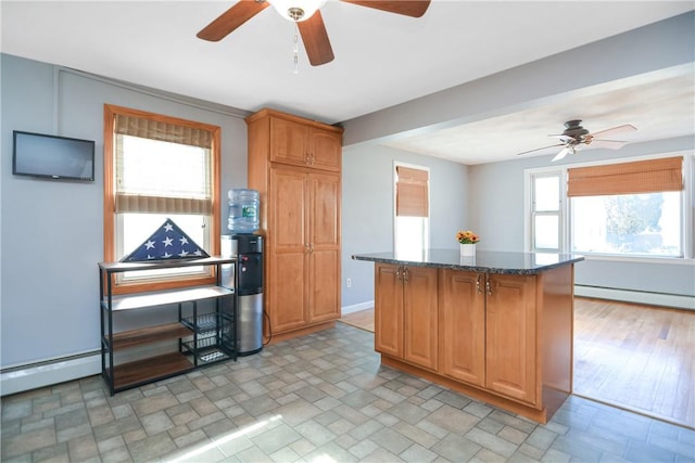 kitchen featuring ceiling fan, dark stone countertops, a kitchen island, and a baseboard heating unit