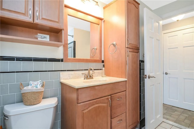 bathroom featuring vanity, tile walls, and toilet