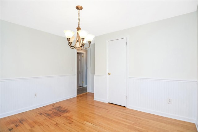 unfurnished room with hardwood / wood-style floors and a notable chandelier